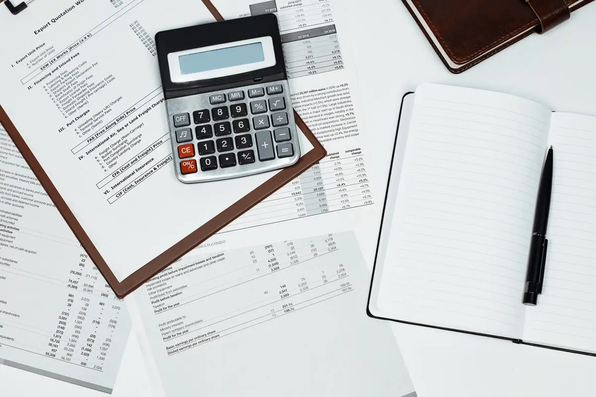 A calculator, notebook and financial papers laid out on a desk
