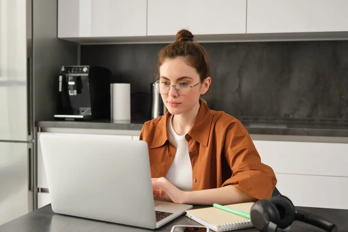 A young woman working confidently on her laptop at home