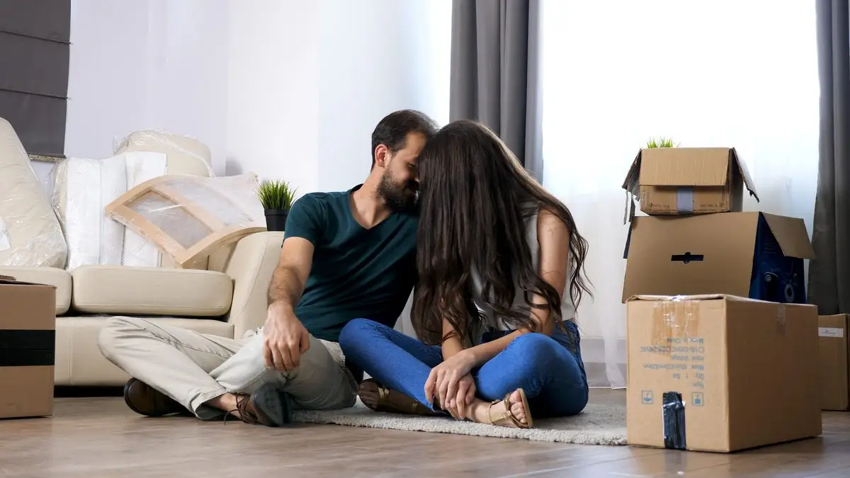 An unmarried couple sitting together on the floor of their home
