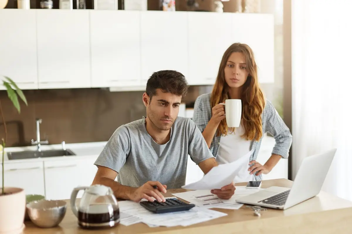 A couple working through a calculator and paperwork at the kitchen table