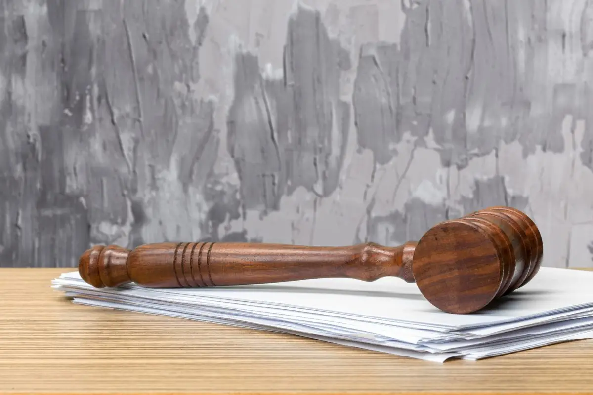A wooden gavel resting on a stack of papers on a desk