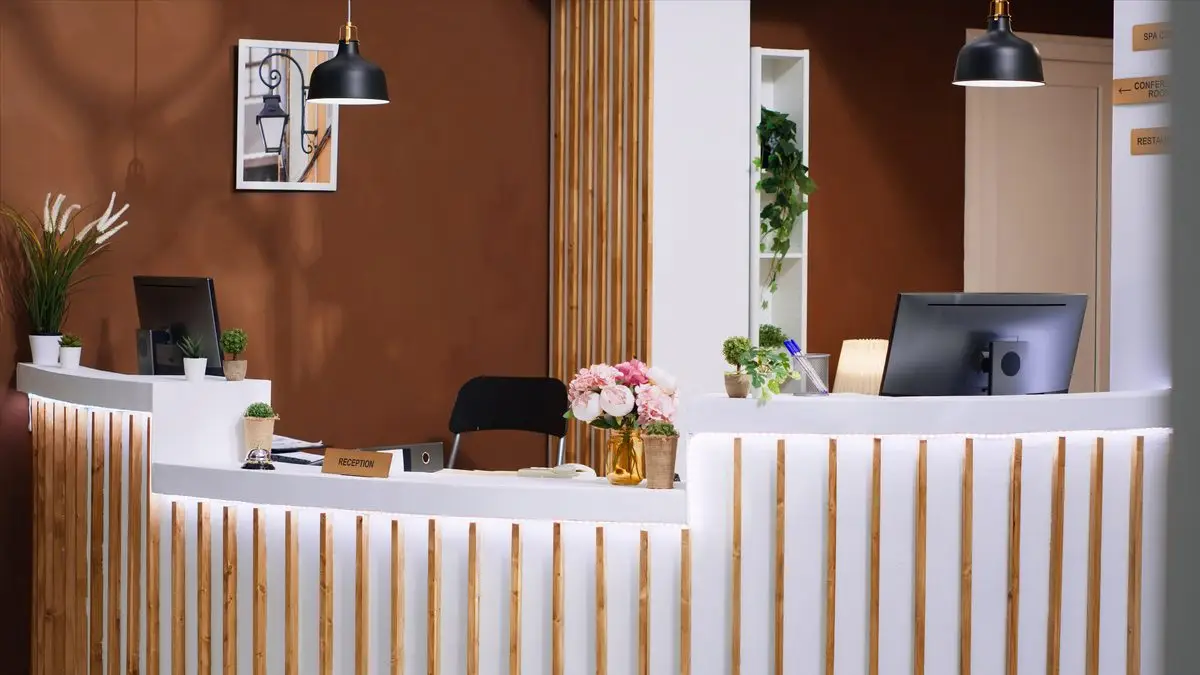 A stylish reception desk with warm wood panelling and a seating area in a professional office